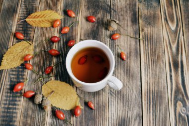 Sonbahar kompozisyon rose hips fındıklı çay yaprakları. Bir fincan çay rose hips ile. Sonbahar sıcak içecek