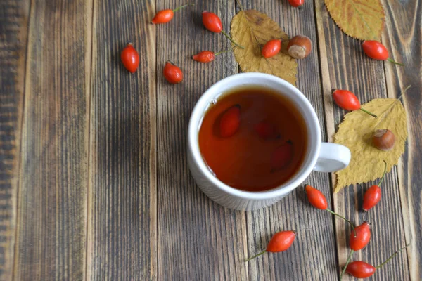 Autumn composition with rose hips nuts leaves a Cup of tea. A Cup of tea with rose hips. Autumn hot drink