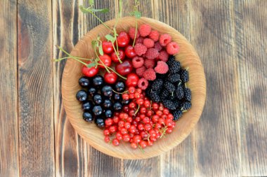 Farklı lezzetli taze yaz meyveleri kiraz, kuş üzümü, ahşap arka plan üst görünümü nde ahşap tabak böğürtlen