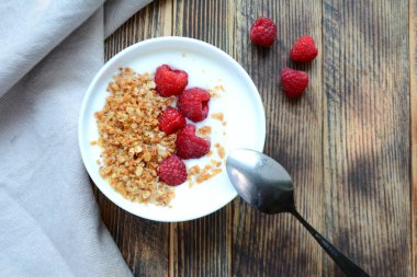 Ahşap bir arka planda bir kase granola ve taze ahududu ile lezzetli yoğurt sağlıklı gıda kavramı üst görünüm