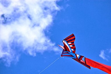 Kırmızı uçurtma bulutlu bir gökyüzüne karşı kaygısız uçuyor.