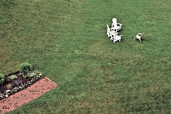 Büyük yeşil çimlerde beyaz sandalyeler. Köşeden çıkan bir yol..