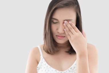 Asian woman suffering from strong eye pain against gray background. Female has a pain in the eye. Healthcare concept. Having migraine clipart