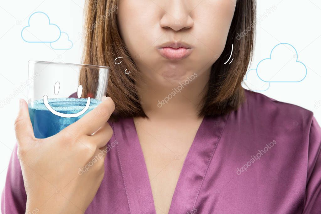 Asian woman rinsing and gargling while using mouthwash.