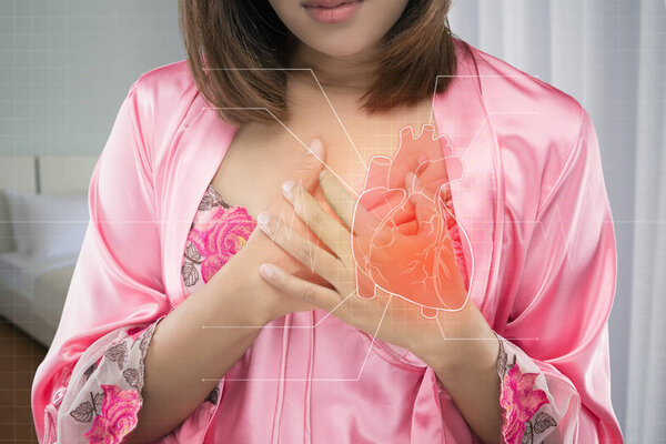 Asian woman in pink satin nightwear her chest pains at night . Acute pain possible heart attack. Heart disease or Heartache