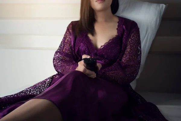 Mulher asiática em roxo camisola de cetim segurando controlador remoto — Fotografia de Stock