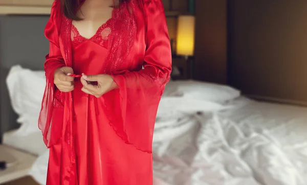 Women wearing red nightgown & long sleeve satin robe with floral lace, A girl trying on new white nightwear for sleep.