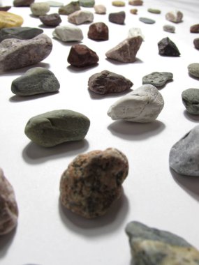 Beyaz bir arka plan üzerinde yatan minerallerin çok renkli küçük doğal taşlar satıriçinde yalan bir koleksiyon.