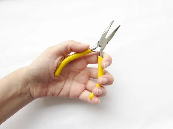 Pinze piccole storte con manici gialli vivaci nella mano sinistra oggetto isolato su sfondo bianco . — Foto Stock