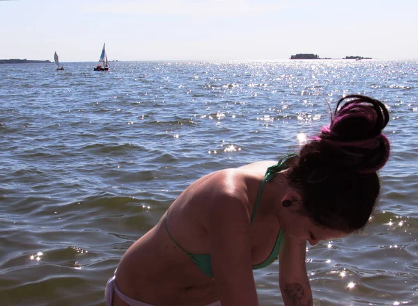 En garvade flicka med lila dreadlocks, tatueringar och en piercing lutade ner mot havet horisonten med små yachter. — Stockfoto