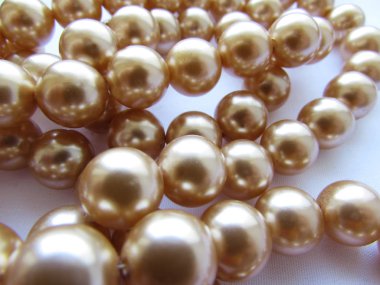 Güzel anne-inci ışık bej pastel büyük boncuklar bir iplik üzerinde beyaz kumaş arka plan üzerinde yalan.