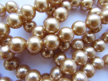 Güzel anne-inci ışık bej pastel büyük boncuklar bir iplik üzerinde beyaz kumaş arka plan üzerinde yalan.