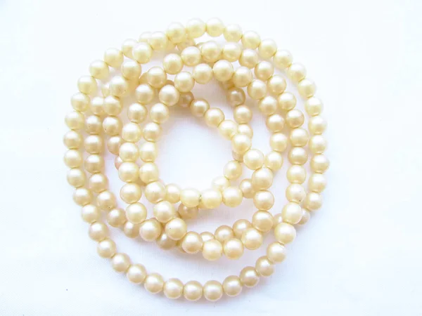 Delicata luce naturale piccola perla perline lunghe accartocciate su uno sfondo bianco . — Foto Stock