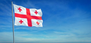 Gürcistan 'ın ulusal bayrağı açık mavi gökyüzünün önünde rüzgarda dalgalanıyor.