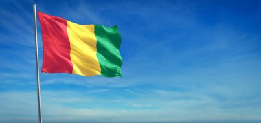 Gine 'nin ulusal bayrağı açık mavi gökyüzünün önünde rüzgarda dalgalanıyor.