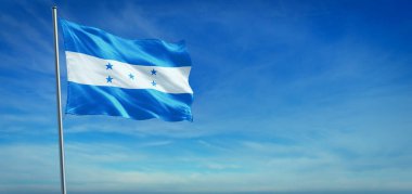 Honduras 'ın ulusal bayrağı açık mavi gökyüzünün önünde rüzgarda dalgalanıyor.