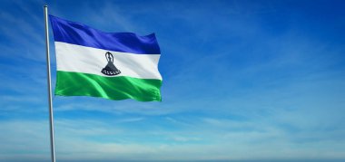 Lesotho 'nun ulusal bayrağı açık mavi gökyüzünün önünde rüzgarda dalgalanıyor.