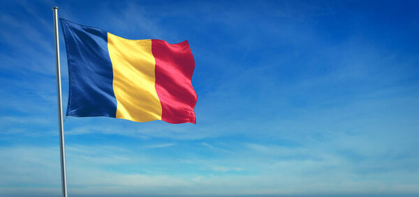 The National flag of Chad blowing in the wind in front of a clear blue sky