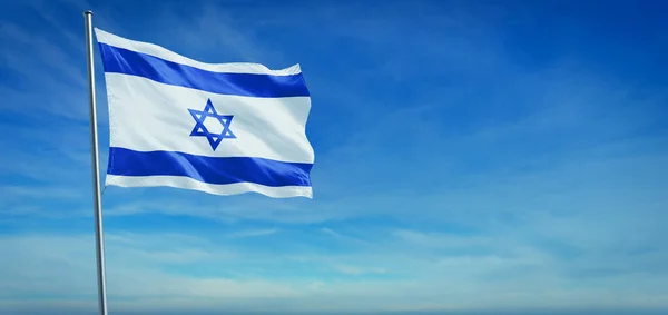 İsrail 'in ulusal bayrağı açık mavi gökyüzünün önünde rüzgarda dalgalanıyor.
