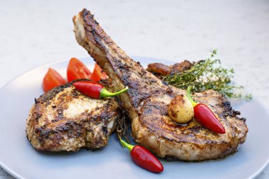 Biber, domates, kekik ve sarımsak ile bir tabakta iki domuz eti biftek