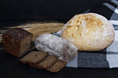 Siyah ve beyaz ekmek buğday kulakları yanında siyah bir zemin üzerine çeşitli farklı türde.