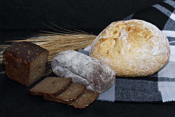 Siyah ve beyaz ekmek buğday kulakları yanında siyah bir zemin üzerine çeşitli farklı türde.