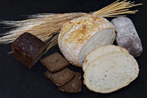 Siyah ve beyaz ekmek buğday kulakları yanında siyah bir zemin üzerine çeşitli farklı türde.