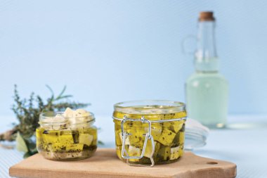 Bir cam kavanoz ve baharat mavi arka plan karşı Marine beyaz peynir.