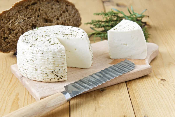 White cheese and bread on a wooden background and greens.
