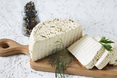 Beyaz peynir ve beyaz zemin üzerine ahşap bir gemide baharat.