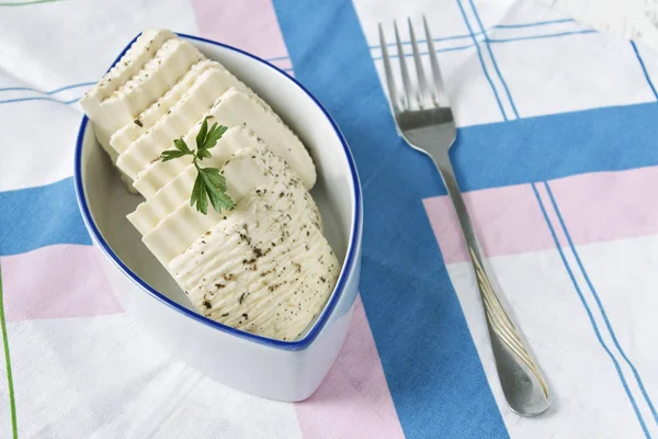 Bir plaka üzerinde bir peçete ve çatal beyaz peyniri dilimlenmiş.