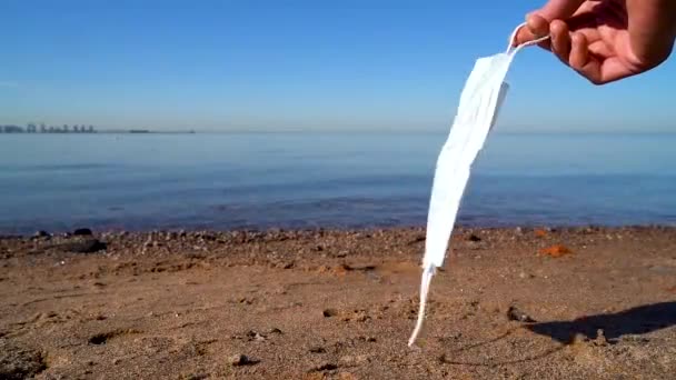 Медицинская Маска Руке Человека Развивается Ветру Фоне Морского Берега Крупным — стоковое видео