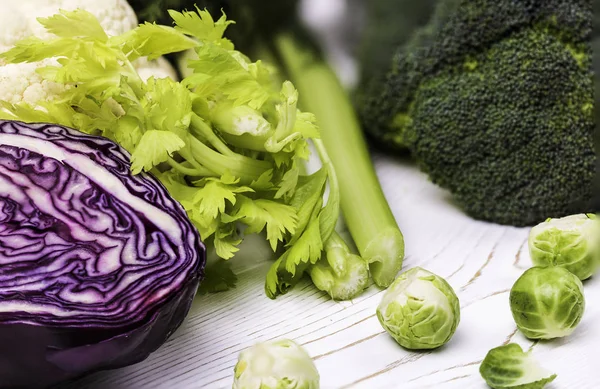 Un primer plano de la cosecha de verduras frescas en una mesa de madera: col, brócoli y coles de Bruselas y col roja, apio - Fondo de alimentación saludable . — Foto de Stock