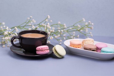 Yakın çekim sabah siyah süt, pasta macaron ve çiçek mavi masada kahve fincan. Güzel tatlı.
