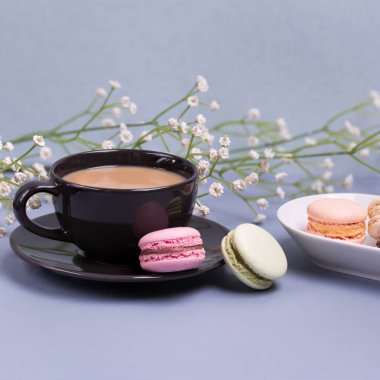 Yakın çekim sabah siyah süt, pasta macaron ve çiçek mavi masada kahve fincan. Güzel tatlı.