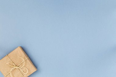 Üstten görünüm hediye veya mevcut kutusu kraft kağıt üzerine pastel mavi arka plan sarılı. Düz styling yatıyordu. Metin için yer kopyalayın