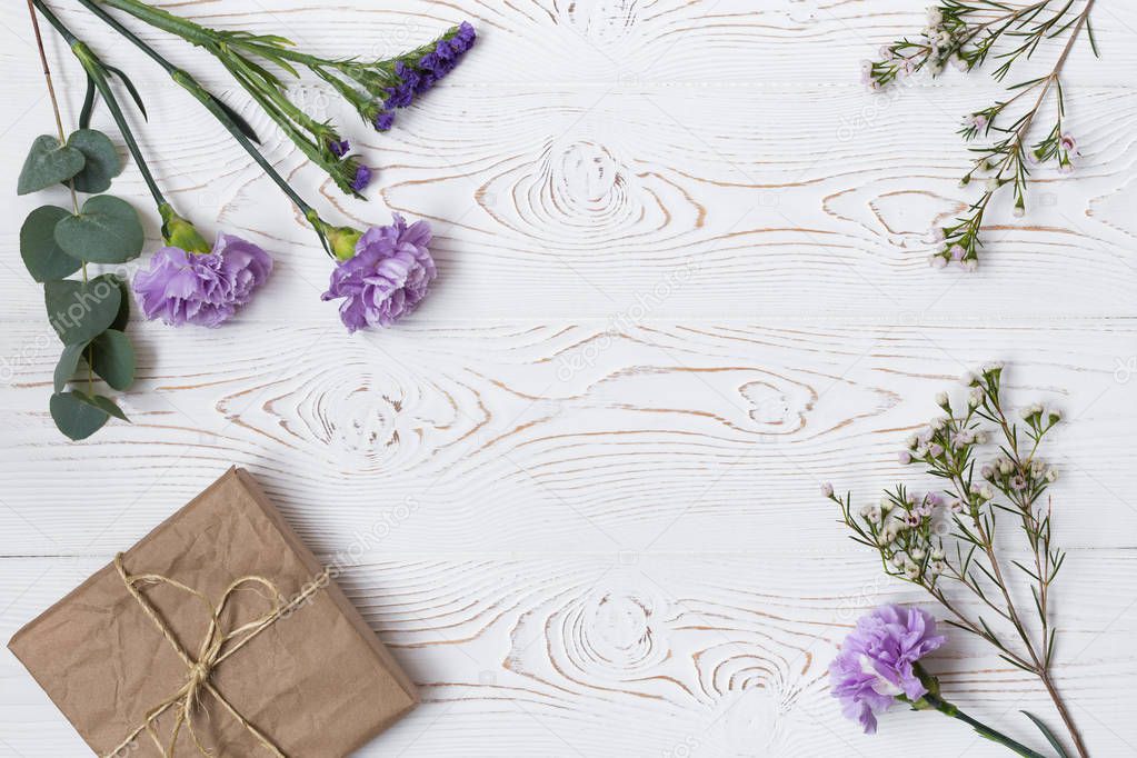 Gift or present box wrapped in kraft paper and flower on white table from above. Flat lay styling. Copy space for text
