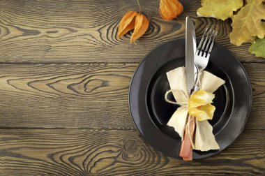 Şükran günü yemeği için sonbahar tablo ayarı. Boş tabak, çatal bıçak takımı, ahşap masa renkli yapraklarda. Sonbahar gıda kavramı