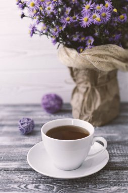 Romantik bir arka plan, bir fincan çay, gri ahşap bir masada vazoda leylak çiçekleri.