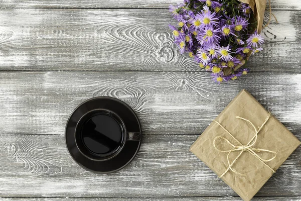 Подарочная или подарочная коробка, завернутая в крафт, чашку кофе и цветок на сером столе сверху. Плоская укладка. Копирование текста . — стоковое фото