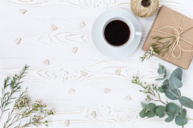 «Ana sayfa» kahve, görünümünü sarılı kraft kağıt, kalpler, beyaz tahta masaya çiçek hediye. Arka plan metin için boş alan ile. Düz yatıyordu