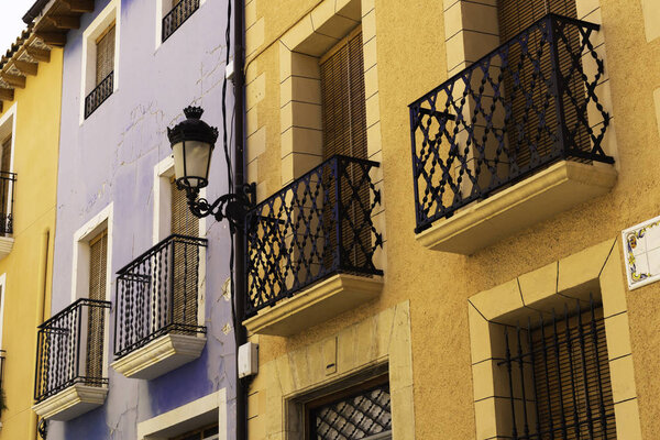 Vintage lantern and beautiful twisted wrought iron balconies on the facade of an old house of a European city.