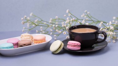 Yakın çekim sabah siyah süt, pasta macaron ve çiçek mavi masada kahve fincan. Güzel tatlı
