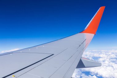 Bulutların mavi gökyüzü ve uçağın kanat manzarası uçak penceresinden.