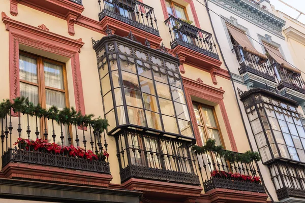 Traditional facades of houses with beautiful wrought iron balconies of the city of Seville, Andalusia, Spain