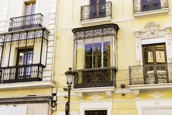 Traditional facades of houses with beautiful wrought iron balconies of the city of Seville, Andalusia, Spain