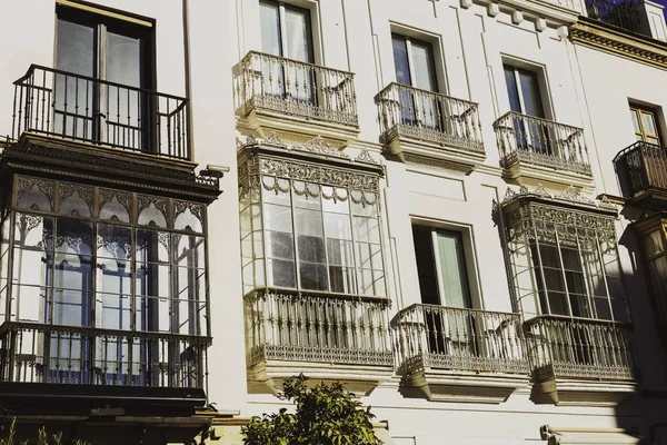 Traditional facades of houses with twisted wrought and carved balconies of the city of Seville, Andalusia, Spain