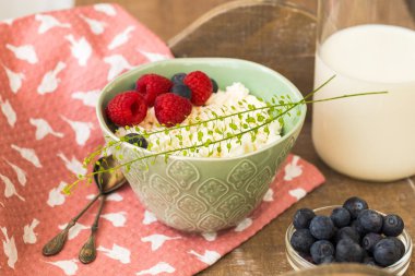 Süzme peynir ile taze Ahududu ve böğürtlen olgun çilek ile sağlıklı bir kahvaltı için bir kapta ve cam şişede süt