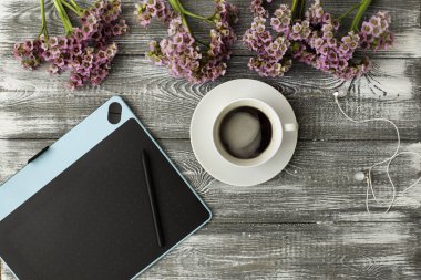 Üstten Görünüm çalışma alanı gracphic tablet ve fincan kahve ve çiçek, gri arka plan üzerinde kopya alanı ile. Düz yatıyordu stil, rustik.