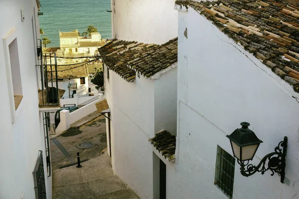 Hermosa calle estrecha en el casco antiguo con casas blancas y una carretera empedrada. Altea, España — Foto de Stock